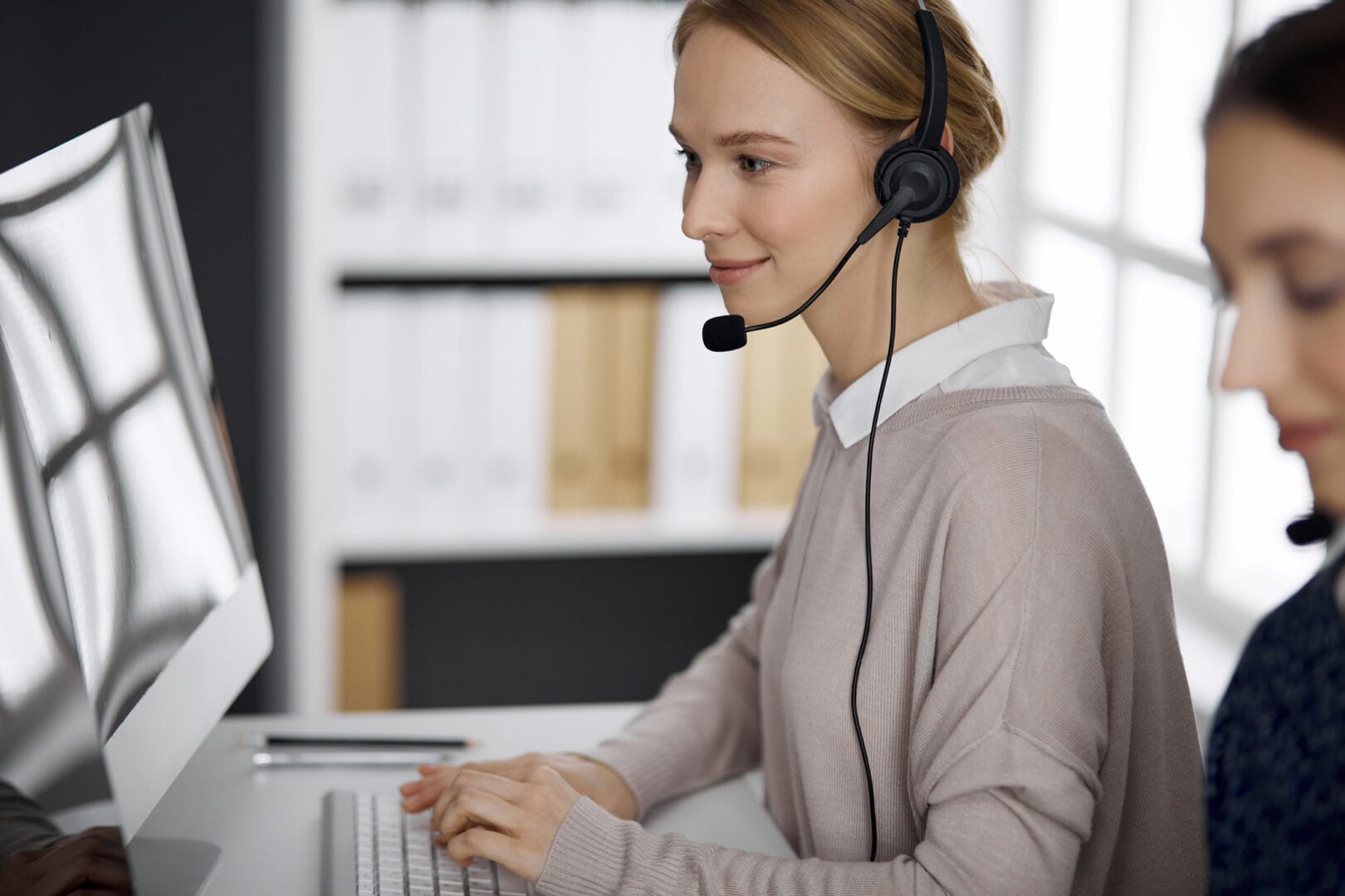 Friendly businesswoman talking by headset in office. call center and diverse people group in business